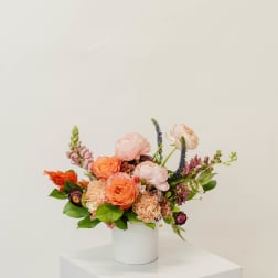 Colorful mixed flower arrangement in a white cylindrical vase