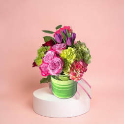 Bouquet of pink roses, purple tulips, and green hydrangeas in a green vase