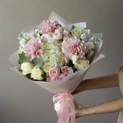 Bouquet of pink and white roses wrapped in pale paper