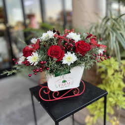Red roses and white daisies in a white holiday container