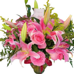 Pink lilies and roses arranged in a glass vase