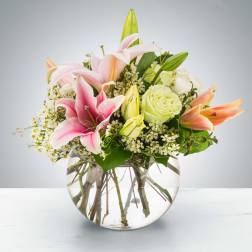 Pink lilies and pale roses in a round glass vase