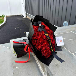 Bouquet of red roses wrapped in black paper with a ribbon