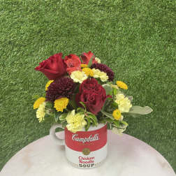 Bouquet of red, yellow, and cream flowers in a Campbell's soup mug