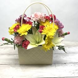 Basket arrangement with yellow daisies, pink carnations, and pale lilies
