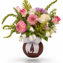 Bouquet of pink and white flowers in a brown vase with a white ribbon