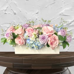 Pastel roses and hydrangeas arranged in a white rectangular box