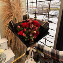 Bouquet of red roses and pink tulips wrapped in black paper