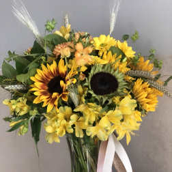 Yellow sunflower bouquet in a glass vase with ribbon