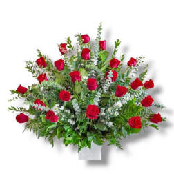 Red roses arranged in a white vase with mixed greenery