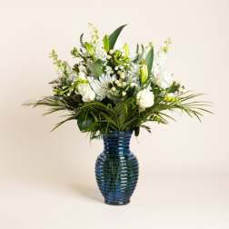 White floral arrangement in a blue glass vase