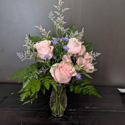Pink roses and purple flowers in a clear glass vase