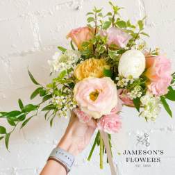 Handheld bouquet of pastel pink, peach, and white flowers
