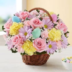 Basket of pink roses, daisies, and yellow carnations with pastel eggs