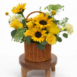 Yellow sunflowers and roses arranged in a wicker basket