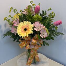 Bouquet of pink lilies and a yellow gerbera daisy in a glass vase