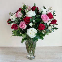 Bouquet of red, pink, and white roses in a clear glass vase