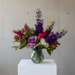 Mixed bouquet of purple, pink, and white flowers in a glass vase
