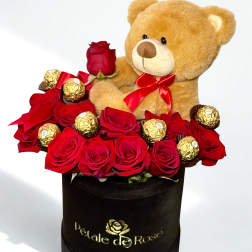 Red roses and chocolates arranged with a teddy bear in a black box