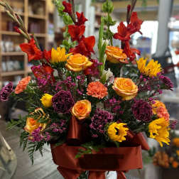 Colorful mixed flower arrangement in a white vase with a red ribbon