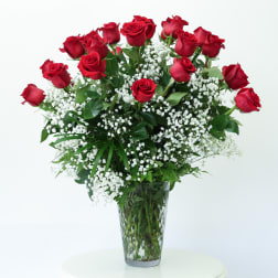 Red roses arranged in a clear glass vase with white baby's breath