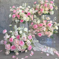 Pink and white rose arrangements with trailing fabric on clear stands