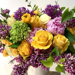 Bouquet of yellow and pink roses with purple flowers in a white vase
