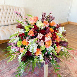 Large floral arrangement with pink, orange, white, and burgundy blooms