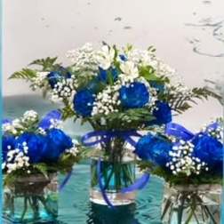 Blue and white flower arrangements in glass vases with ribbon