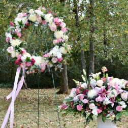 Three pink and white floral wreaths and a matching centerpiece outdoors
