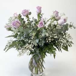 Lavender roses in a clear glass vase with baby's breath