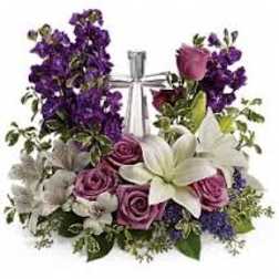 Purple and pink floral arrangement with white lilies and roses in a clear vase