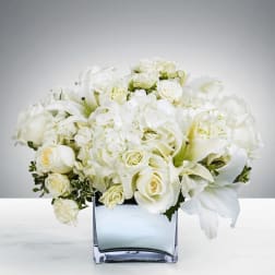 White roses and lilies arranged in a square glass vase