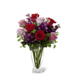 Tall clear vase with red and lavender roses mixed with purple flowers