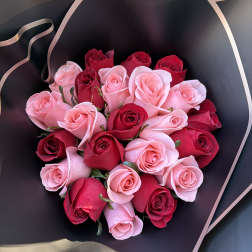 Bouquet of pink and red roses wrapped in black paper