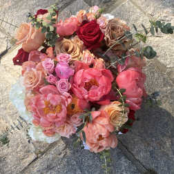 Round bouquet of pink, peach, and red flowers with eucalyptus