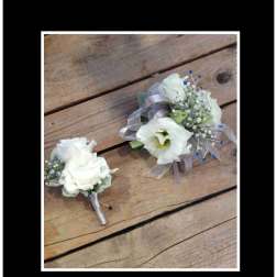 White floral corsage and boutonniere with ribbon on wood