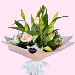 Bouquet of pale pink roses and white lilies wrapped in blush paper