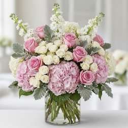 Pink and white roses with hydrangeas in a clear glass vase