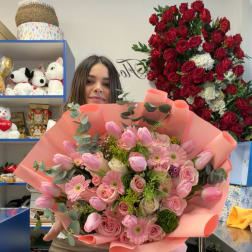 Woman holding a large pink bouquet of roses, tulips, and daisies