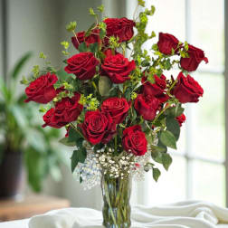 Red roses arranged in a clear glass vase with baby's breath