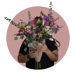 Large bouquet of pink, purple, and white flowers wrapped in paper