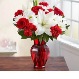 Red roses, white lilies, and white daisies in a red glass vase