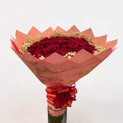 Red roses in a glass vase with pink wrapping and ribbon