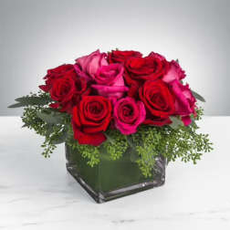 Red and pink roses arranged in a square glass vase