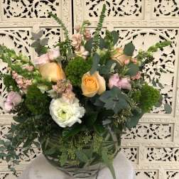 Mixed bouquet of peach and pink roses in a glass vase