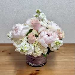 Blush pink roses and white peonies in a purple glass vase