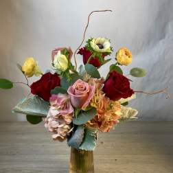 Mixed bouquet of roses, hydrangeas, and anemones in a glass vase