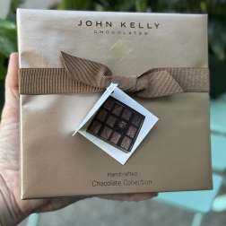 Box of assorted chocolates with a brown ribbon and gift tag