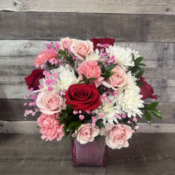 Bouquet of red, pink, and white flowers in a purple glass vase